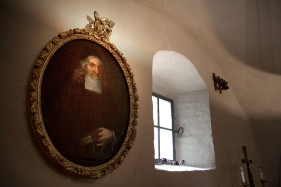 Ett porträtt av prästen Lars Weldt från 1721 hänger intill sakristians fönster.