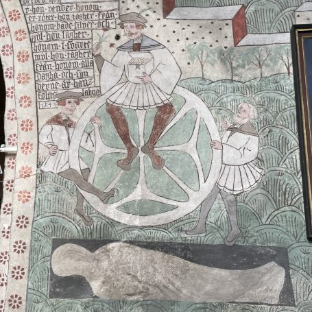 Medeltida målning av ett stort hjul där tre män befinner sig på olika delar av hjulet. En död person ligger under hjulet.