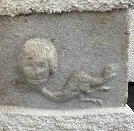 Stenrelief  i form av ett människoansikte och ett reptilliknande djur